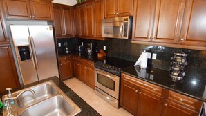 Una cocina con gabinetes de madera, electrodomésticos de acero inoxidable, encimera de granito y horno empotrado.