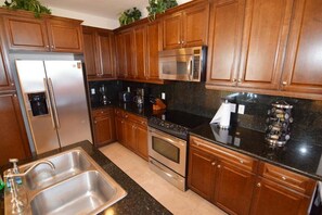 Eine Küche mit Holzschränken, Edelstahlgeräten, einer Granit-Arbeitsplatte und einem eingebauten Backofen.