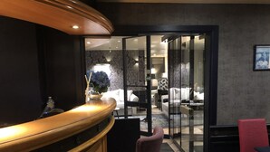 Un hall d’hôtel comprenant un comptoir d’accueil, un espace salon et un aperçu de la chambre adjacente.