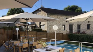 Une terrasse extérieure avec des tables et des chaises, des parasols, et un bâtiment en pierre en arrière-plan.