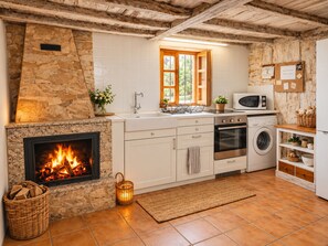 Une cuisine avec un mur en pierre, une cheminée, une fenêtre et un four à micro-ondes.