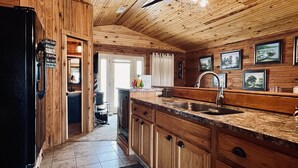 L’intérieur d’une cabane en bois comprend une cuisine équipée d’un évier, de placards et d’un réfrigérateur.