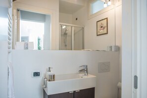 Ein modernes Badezimmer mit Waschbecken, Spiegel und Dusche.