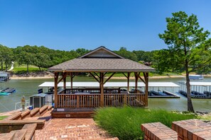 A gazebo with a brick patio, overlooking a lake with docks and boats.