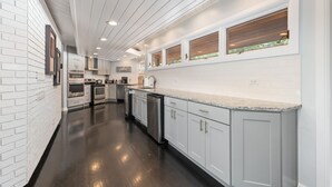 Une cuisine moderne avec des meubles blancs, un plan de travail en granit et un sol noir.