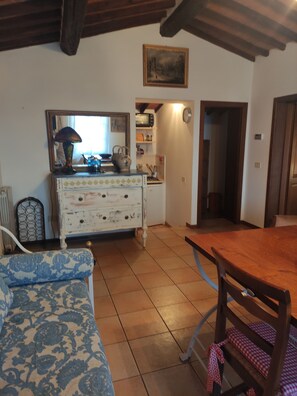 A cozy kitchen with a wooden table, a patterned sofa, and a vintage dresser.
