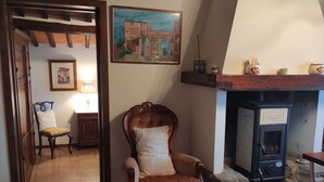 A cozy living room with a wooden chair, a fireplace, a painting on the wall, and a tiled floor. - Casa Crevole in Val di Merse (Murlo)