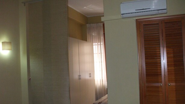 A bedroom with a bed, a wardrobe, a bedside table, and an air conditioning unit. - one bedroom apartment in central location (messina)
