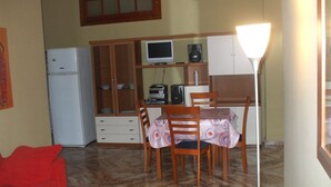 A compact kitchen with a dining table, chairs, a refrigerator, and a television. - one bedroom apartment in central location (messina)