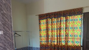 Un bagno con doccia, un letto con lenzuola a motivi floreali e una tenda colorata.