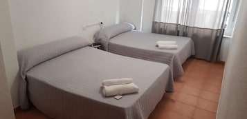 Una habitación con dos camas individuales, cada una con una almohada y una toalla enrollada.