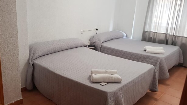 A hotel room with two single beds, each with a pillow and a rolled towel. - Hostal Plaza de España (Salamanca)