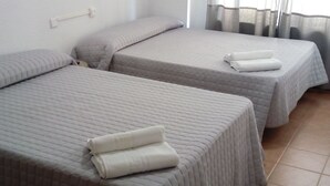 A room with two beds, each with a quilted mattress and pillows, and a window with sheer curtains. - Hostal Plaza de España (Salamanca)