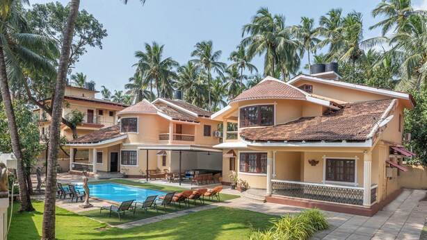 A resort with multiple two-story buildings, a swimming pool, and palm trees.