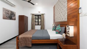 A neatly arranged bedroom with a bed, a wardrobe, a bedside table with a lamp, a ceiling fan, and a window with curtains.
