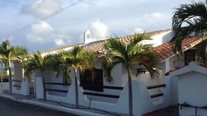 Un bâtiment blanc avec un toit en tuiles et des palmiers devant.