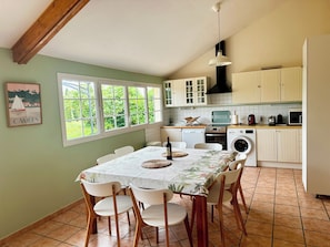 A kitchen with a dining area, a washing machine, and a large window.