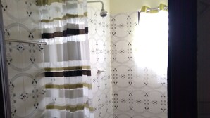 Ein Badezimmer mit gemusterten Fliesen, einer Duschvorhang und einem gefliesten Boden.