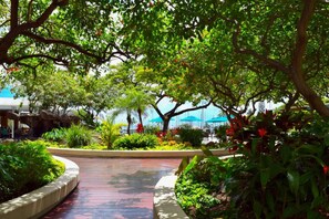 A lush garden pathway with a curved design, surrounded by various plants and trees. - 1519 · Ilikai Collection # 9. Beachfront Resort, upgraded (Honolulu)