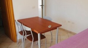 Een kleine kamer met een houten tafel en twee stoelen.