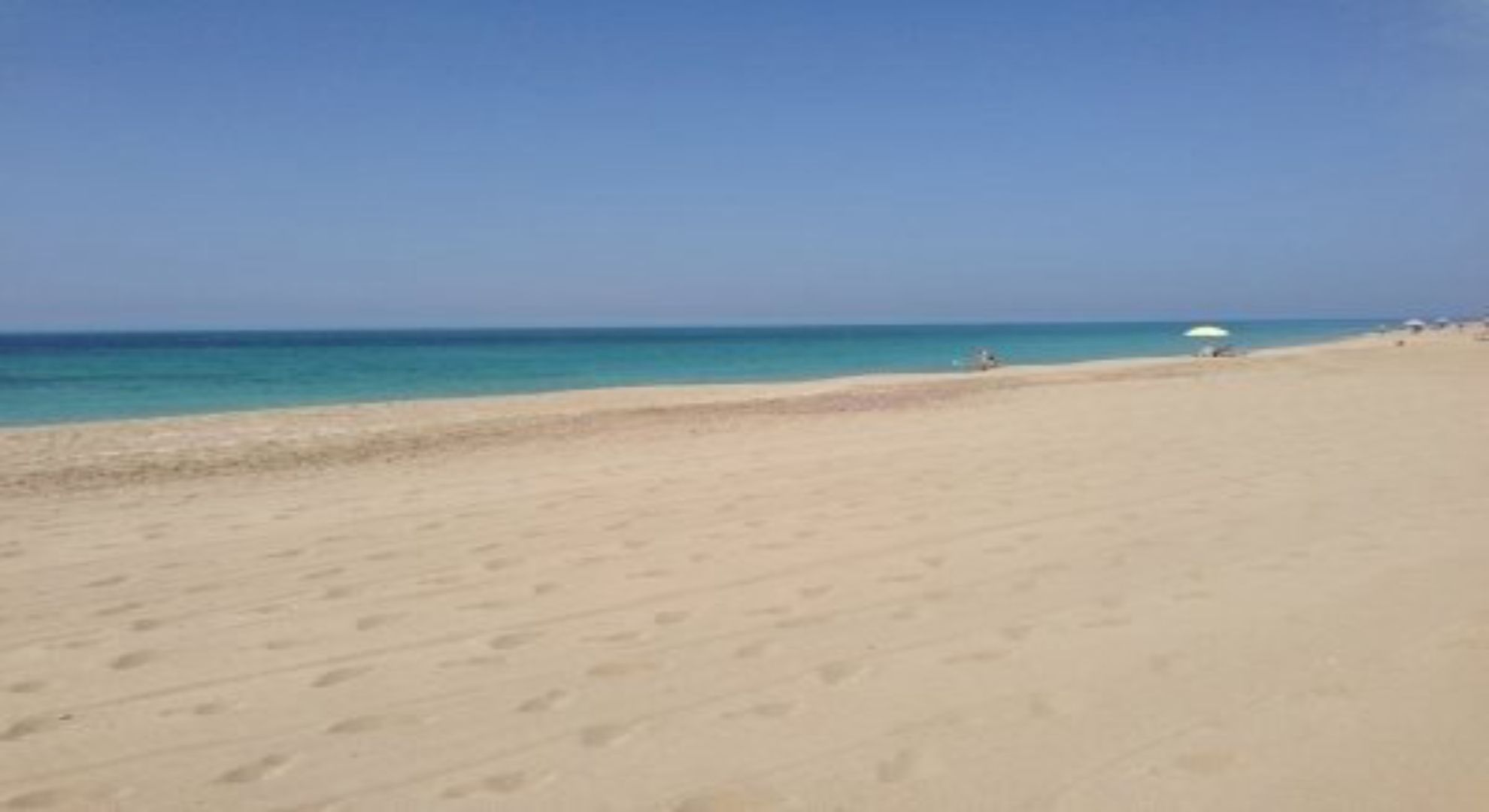 Une plage avec un ciel dégagé et une mer calme.
