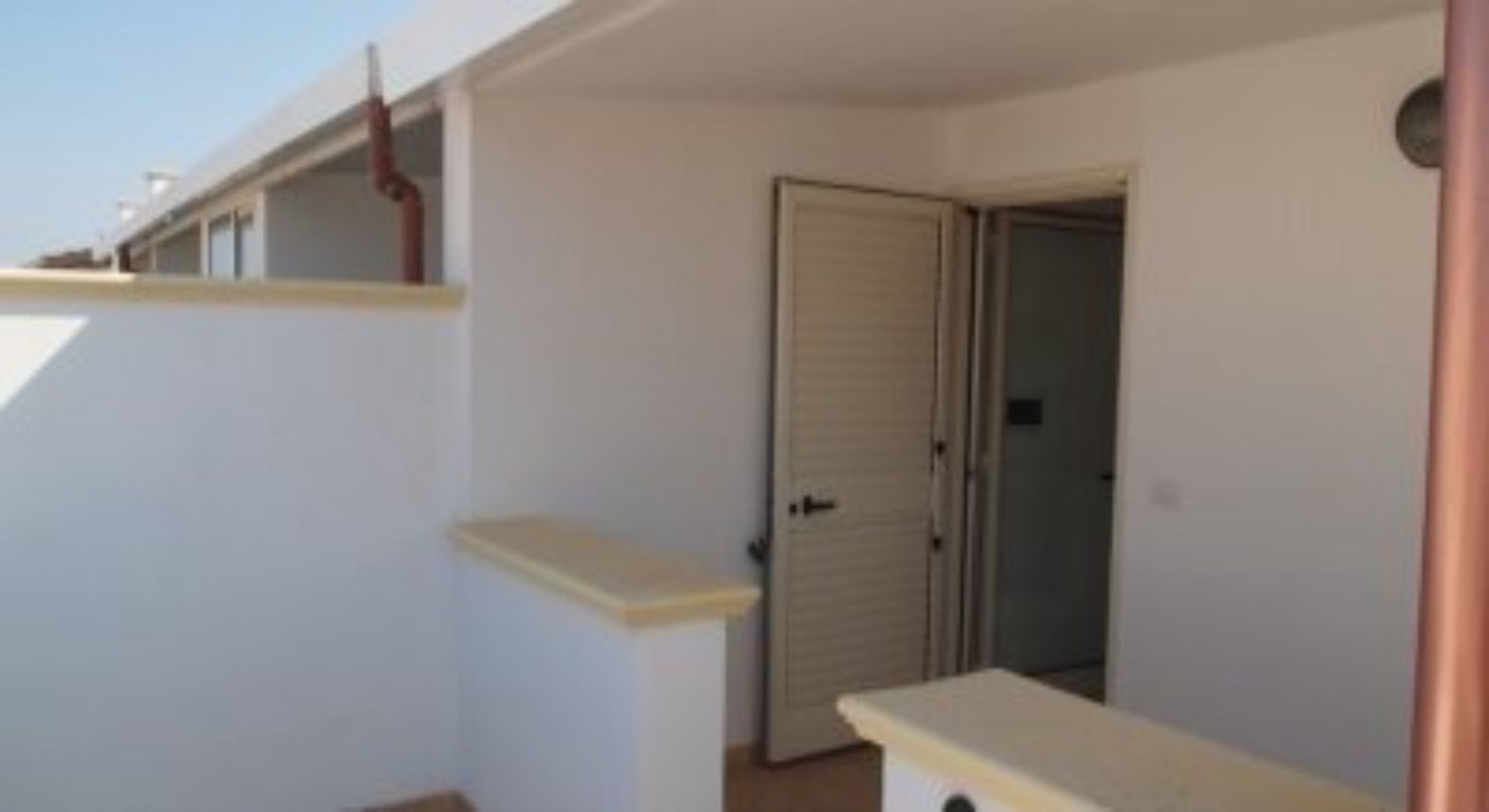 Ein Zimmer mit einer Tür, einem kleinen Fenster und einer weißen Wand.