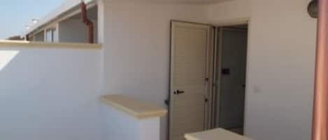 A room with a door, a small window, and a white wall.
