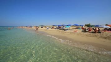 Uma praia com águas cristalinas, pessoas e guarda-sóis.