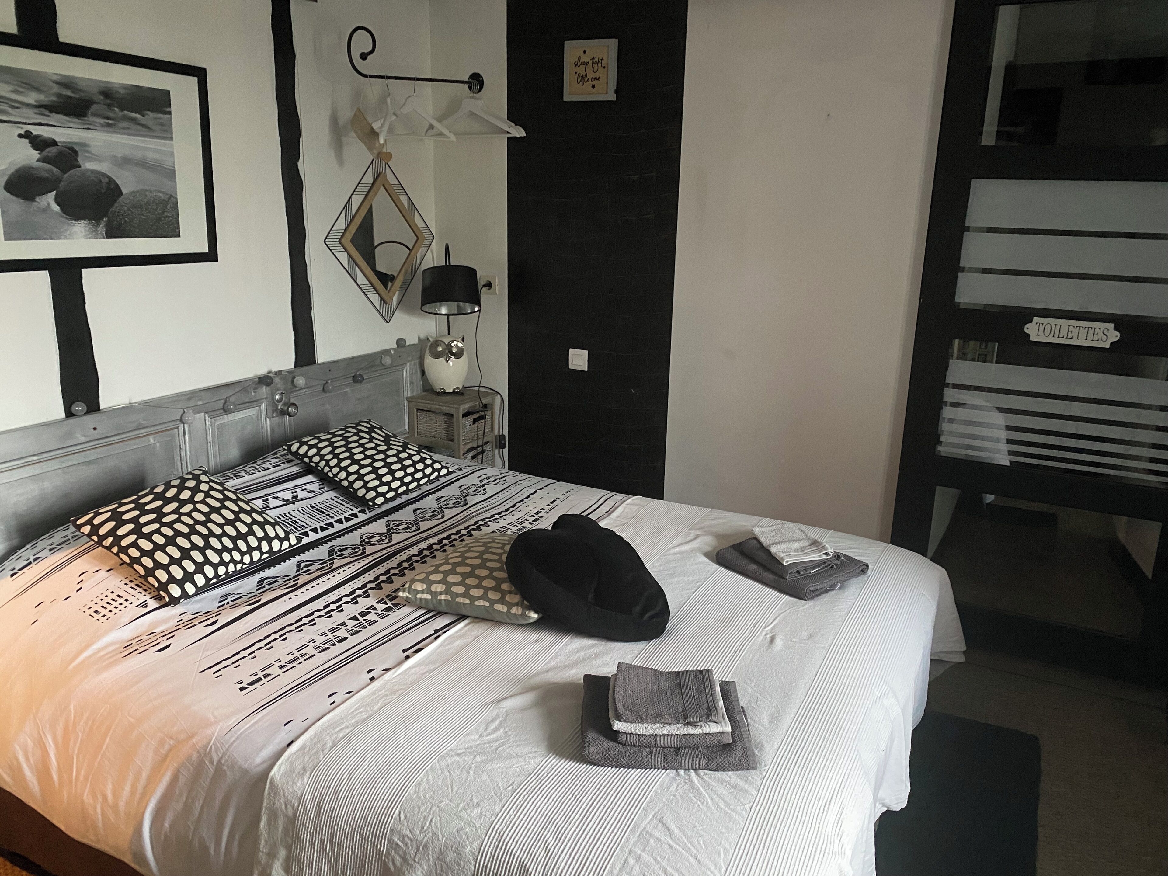 A neatly made bed with patterned bedding, a bedside lamp, and a framed picture on the wall.