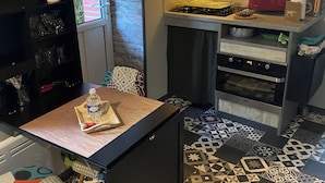 Een kleine keuken met een gasfornuis, een rode broodrooster en een vloer met een patroon.