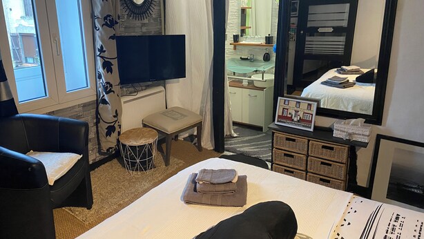 Een hotelkamer met een bed, een televisie, een klein tafeltje, een stoel, een spiegel en uitzicht op buiten.