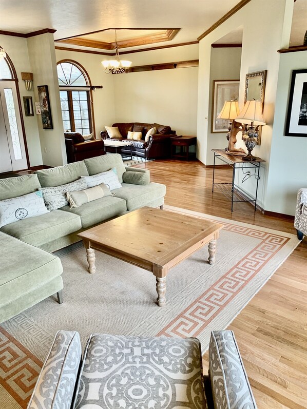 A spacious living room with a large sectional sofa, a wooden coffee table, and a patterned rug.