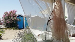 A covered outdoor seating area with a transparent canopy, a white chair, and a decorative branch. - Villa near the sea, Cinquale Forte dei Marmi (CINQUALE)