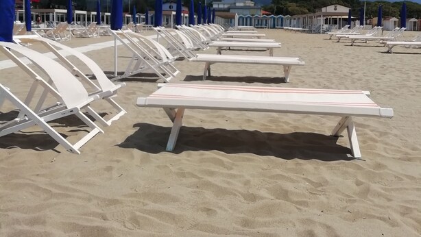 A beach with rows of white sun loungers and blue umbrellas, with mountains in the background. - Villa near the sea, Cinquale Forte dei Marmi (CINQUALE)