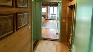 Un couloir en bois, avec des tableaux encadrés accrochés aux murs, un tapis sur le sol et une porte donnant sur une autre pièce.