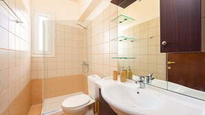 A bathroom with a toilet, shower, sink, and mirror. - Apollon - Seven Springs Villas (Rhodes)