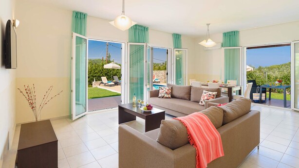 A modern living room with a sofa, coffee table, and dining area. - Apollon - Seven Springs Villas (Rhodes)