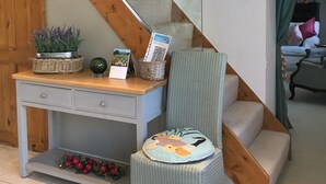 Un escalier avec des marches en bois et une rampe en verre, menant à une pièce où se trouvent un bureau, une chaise et des objets décoratifs.