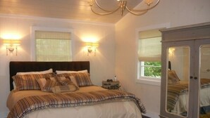 Une chambre à coucher comprenant un lit, deux lampes fixées au mur, une table de chevet et une commode avec un miroir.