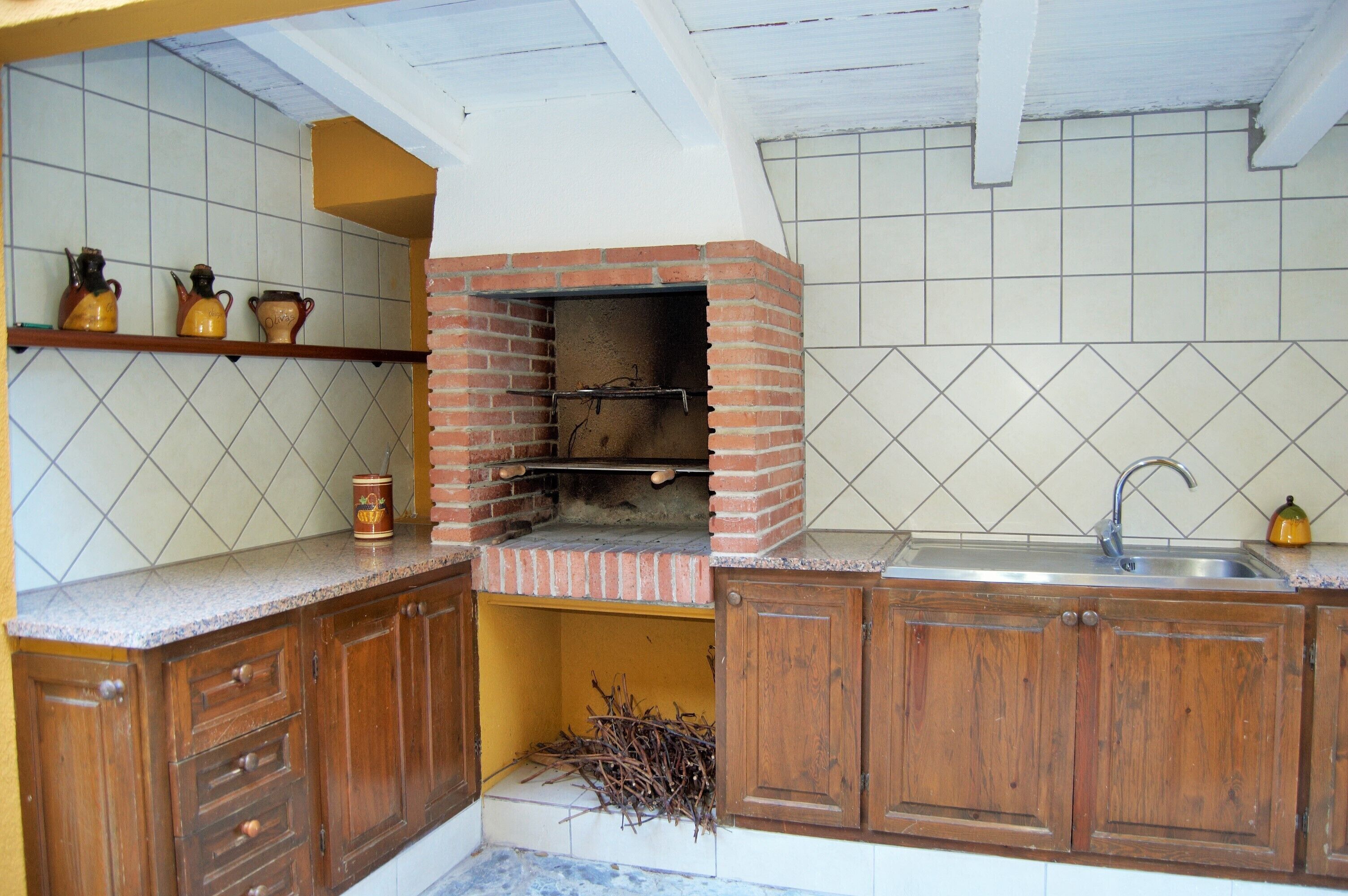 A kitchen with a brick oven, wooden cabinets, and a tiled backsplash.