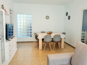 Un espace repas comprenant une table, des chaises, un téléviseur et une bibliothèque.