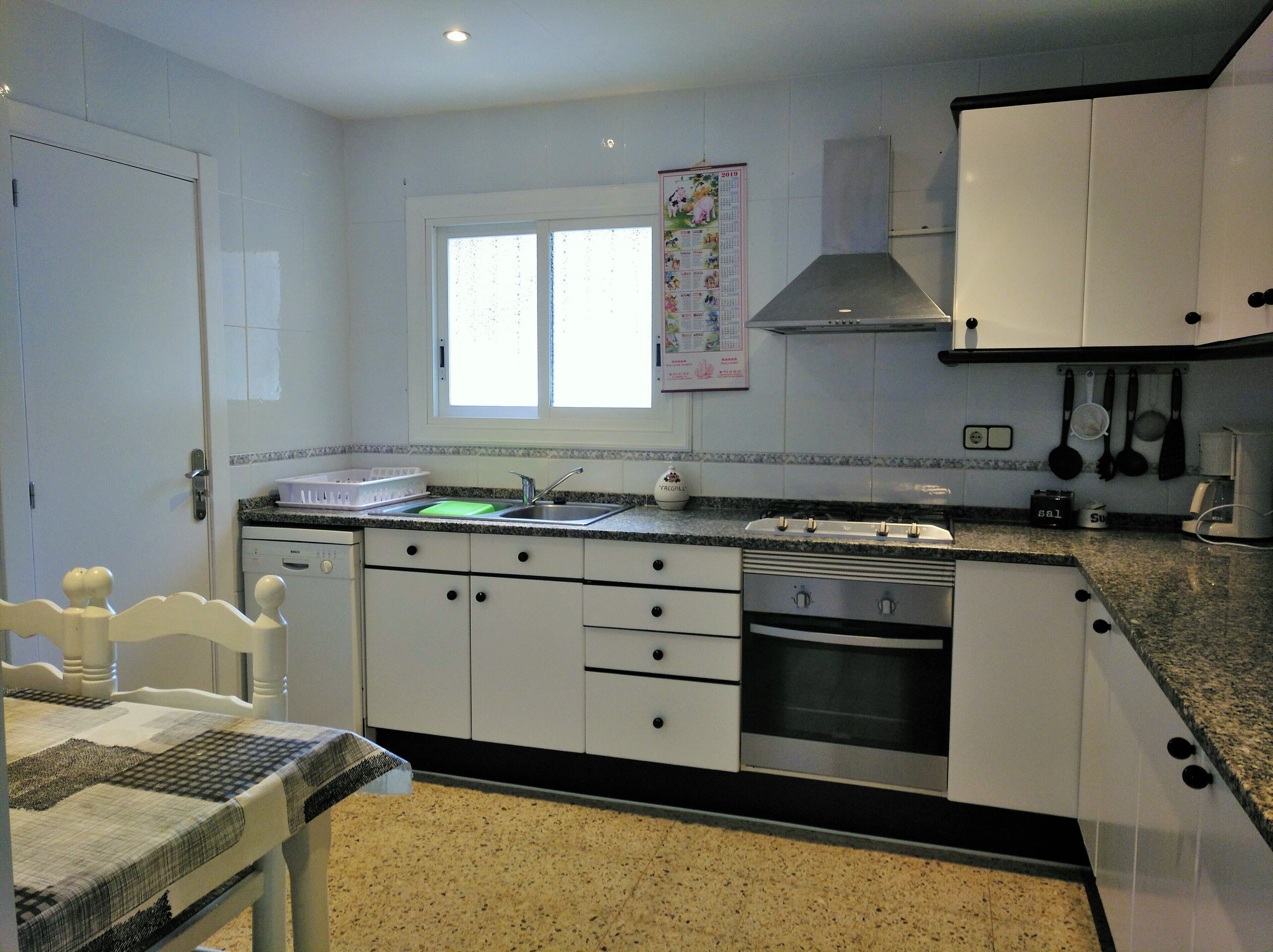 A kitchen with white cabinets, a stainless steel sink, and a window above the countertop.