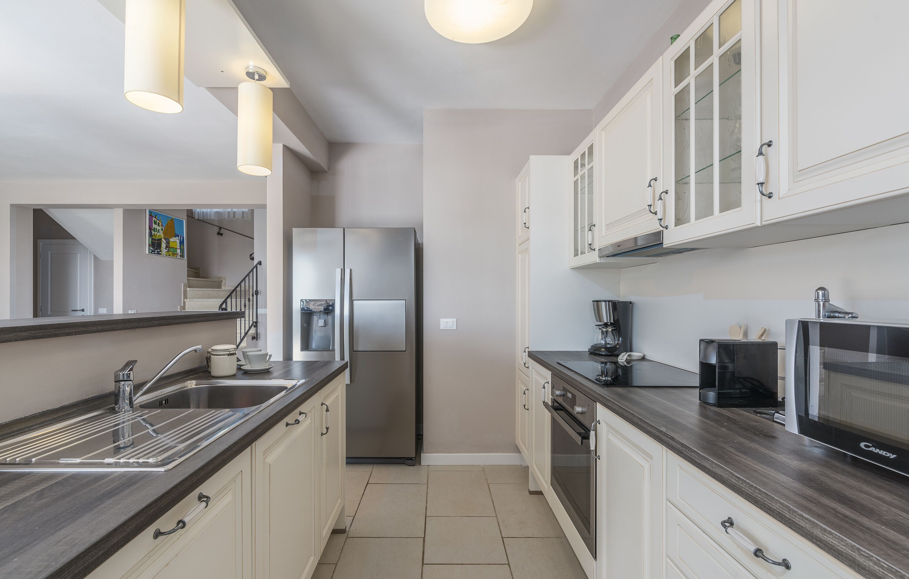 A modern kitchen with stainless steel appliances, white cabinetry, and a dark countertop.