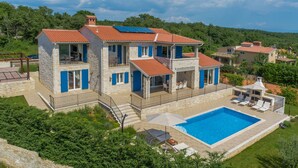 Una casa de pedra de dos pisos amb piscina, balcons i panells solars.