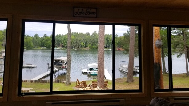 Eine Hütte mit einem großen Fenster mit Blick auf einen See, umgeben von Bäumen.