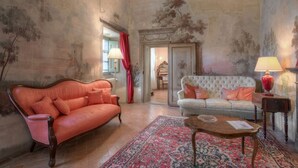 A room with a large red sofa, a white sofa, a wooden coffee table, and a patterned rug. - CastellodiSarna, Montini House (Sarna, Chiusi della Verna)