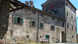 A stone building with green shutters, a cart, and a cobblestone street. - CastellodiSarna, Montini House (Sarna, Chiusi della Verna)