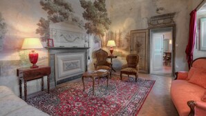 A room with a fireplace, two lamps, a patterned rug, and a sofa. - CastellodiSarna, Montini House (Sarna, Chiusi della Verna)