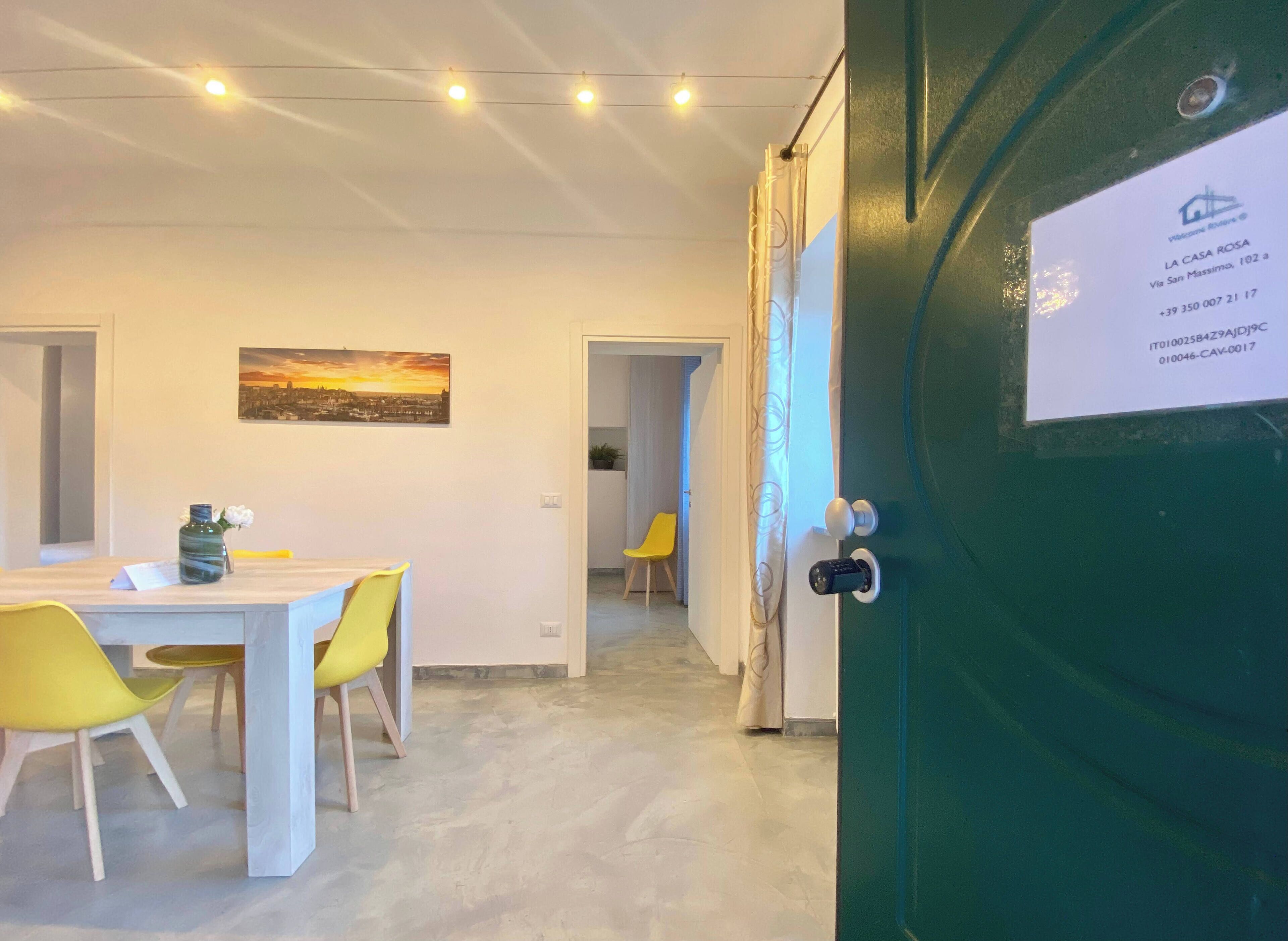 Ein modernes Hotelzimmer mit Essecke, einem Gemälde an der Wand und einer grünen Tür mit Sicherheitstechnik.