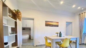 A modern room with a dining table, yellow chairs, a bed, and a painting on the wall. - Casa Rosa, Rapallo (rapallo)